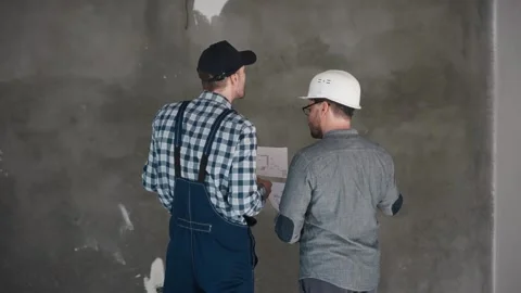 Two construction workers are standing next to each other in front of a wall Stock Footage 294162052