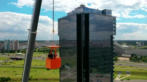 Two construction workers in the building cradle of a mobile crane. Aerial view. Video stock 138078208