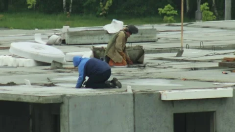 Two construction workers busy on concrete roof of panel house building under Stock Footage 342922201