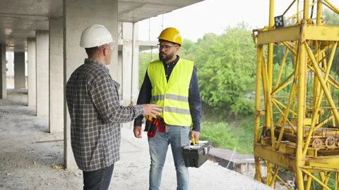Two construction workers discussing a project at the building site Stock Footage 343450718