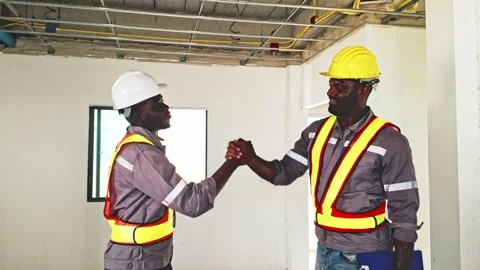 Two construction workers in hard hats and reflective vests shake hands. Stock Footage 311374862