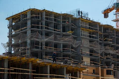 Two construction workers in helmets stand at the edge of a house under Stock Photos