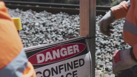 Two construction workers in high-visibility clothing install a ‘Confined Space’ Stock Footage 305535404
