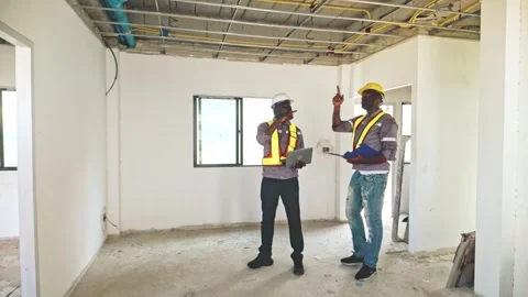 Two construction workers inspect ceiling wiring inside a house under renovate. 스톡 동영상 312617421