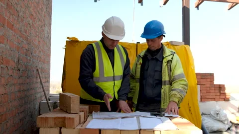 Two construction workers Looking on Blueprint Project Plans on construction Stock Footage 258111444