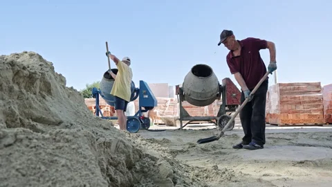 Two Construction Workers Mixing Concrete With Shovels And Cement Mixer On Stock Footage 315382546