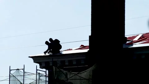 Two construction workers repairing red metal roof. Russia - 22 September 2026 Stock Footage 341833437