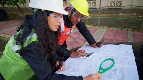 Two construction workers reviewing blueprints outdoor Stock Footage 302634907