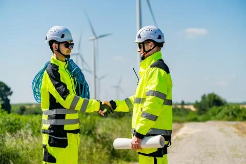 Two construction workers in safety gear shake hands at a renewable energy s.. Stock Photos