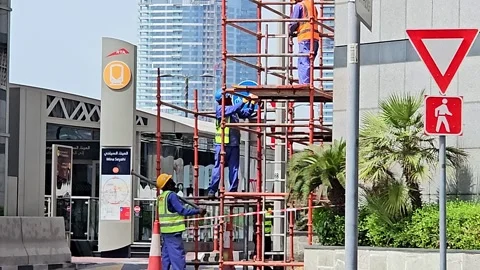 Two construction workers on scaffolding, one in a yellow vest Stock Footage 311590809