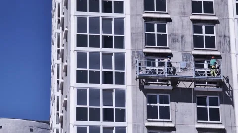 Two construction workers on suspended scaffold platform perform exterior Stock Footage 344846775
