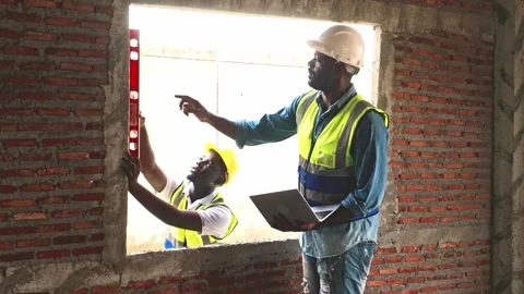 Two construction workers use a level tool to check window alignment inside. Stock Footage 311374865