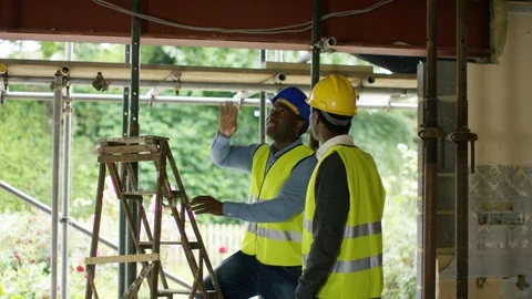Two constructions engineers discussing while looking at ceiling at site Stock Footage 108143941