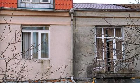 Two contrasting building facades with windows and bare tree branches Stock Photos