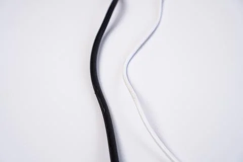 Two contrasting electrical cords, one solid black and one solid white, curv.. Stock Photos