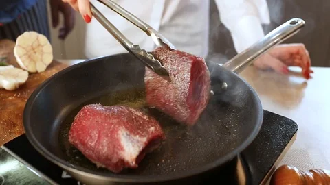 Two cooks cook meat on a frying pan Stock Footage