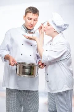 Two cooks in suits try the cooked soup in the commercial kitchen Stock Photos