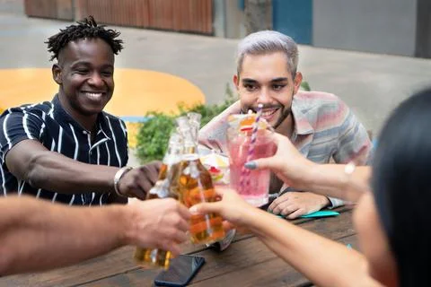 Two cool casual happy friends having a drinks in a terrace. Black male and Stock Photos