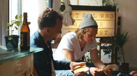 Two Cool Caucasian Men Looking at Art Prints Stock Footage 64964597