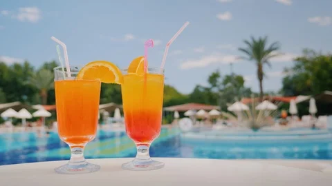 Two cool cocktails stand on the table on the background of the pool and palm Stock Footage 91509028