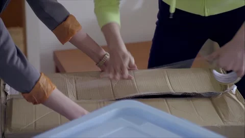 The two cooperate to seal the cardboard box Stock Footage 265537500