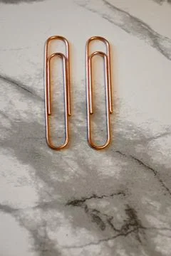 Two copper paper clips on marble surface 库存照片