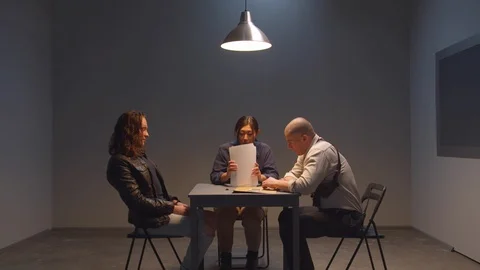 Two cops pull information from a criminal Stock Footage 128630568