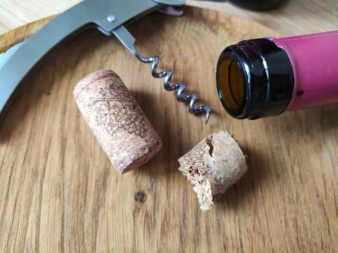 Two cork stoppers, corkscrew and the neck of a wine bottle Stock Photos