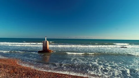 Two Cormorants resting on a large pillar of concrete near the beach . aerial 4k Stock Footage 83670398