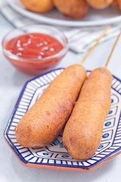 Two corn dogs on white blue plate, served with ketchup, vertical Foto stock