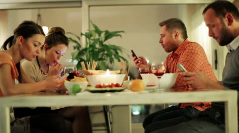 Two couple eating dinner drinking wine and busy on smartphones. Видео 36713377