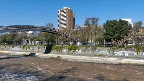 Two couples cross bridge over the shallow, calm brown water Stock Footage 97116068