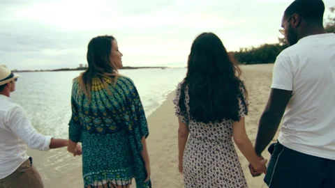 Two couples, holding hands, walking barefoot on the beach, talking and smiling, Stock Footage 199457600