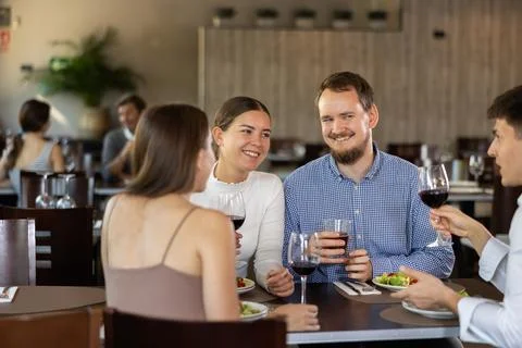 Two couples meet for dinner at restaurant. They chat and drink wine Stock Photos