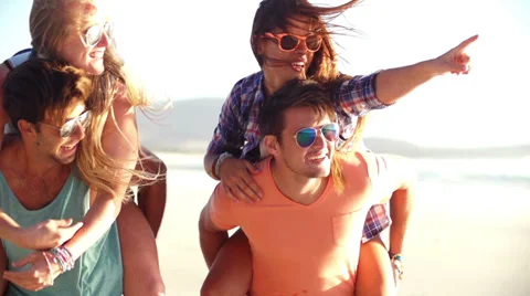 Lovely gay couple on piggyback ride at the beach. Stock Photo