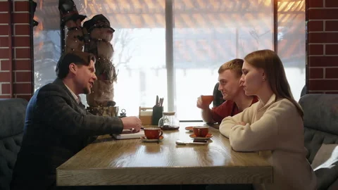 Two couples sit at cafe table having animated conversation with gestures during Stock Footage 322094967