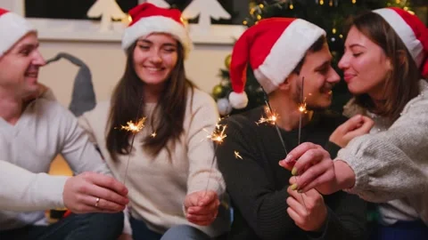 Two couples sitting close to each other on Christmas eve at home with a sparkler Stock Footage 165349700