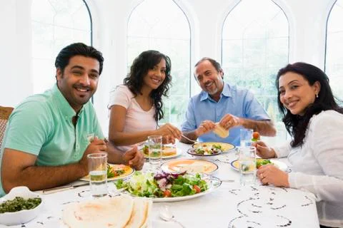 Two couples sitting at dinner table smiling (high key) Stock Photos