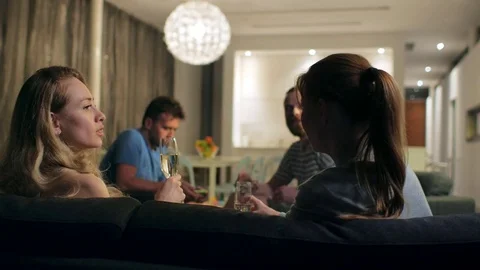 Two couples spend an evening in a cozy livng room, they communicate and drink Stock Footage