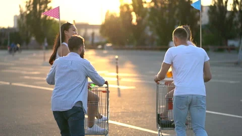 Two couples of young friends walking with carts at the parking. Stock Footage 109817521