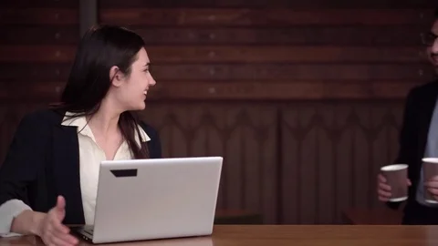 Two coworkers begin to discuss cases in front of laptop with coffee Stock Footage 85404490