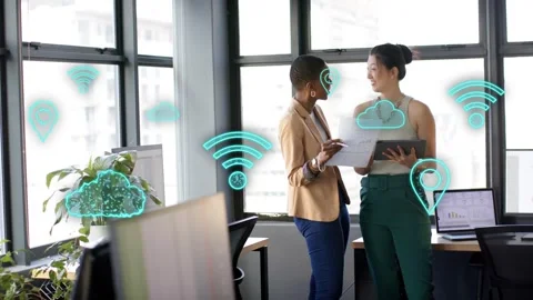 Two coworkers reviewing docs, tapping tablet, initiating cloud Wi-Fi icons over Stock Footage 333575195