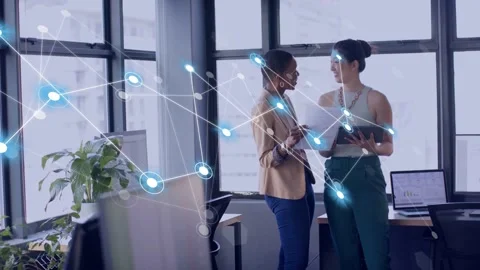 Two coworkers sharing papers and tapping tablet sparking blue node overlay Stockbeeldmateriaal 333950517