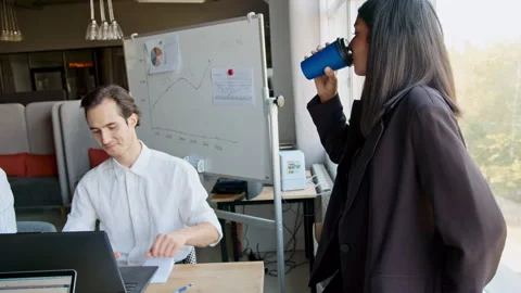 Two coworkers talk about a project in an office setting. They share ideas and 스톡 동영상 335748447