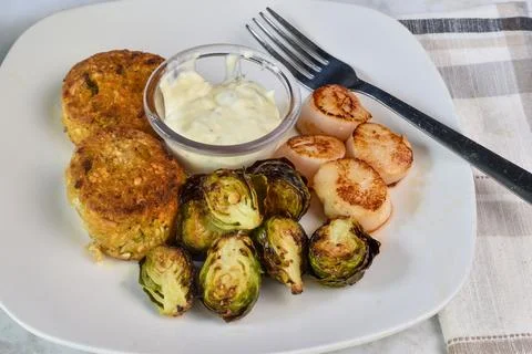 Two crab cakes served with sheared scallops Stock Photos