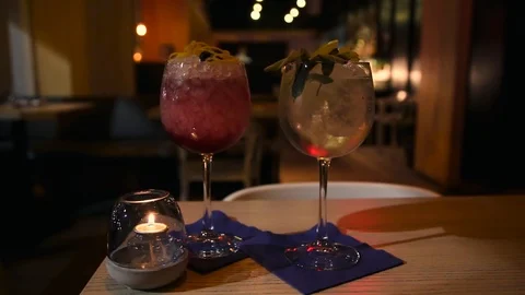 Two craft cocktail drink in a upscale cocktail lounge and a woman's hand picking Stock Footage 99161607