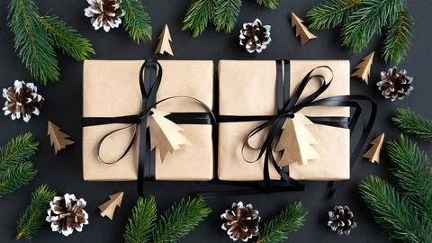Two craft gift boxes with black ribbon on dark background with fir and cones Stock Photos