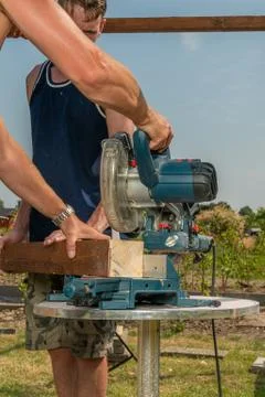 Two craftsmen are working on a circular saw to saw beams Stock Photos
