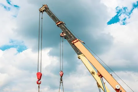 Two crane arrows with hooks on the sky background Stock Photos