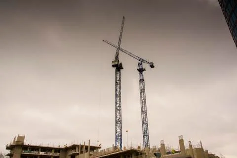 Two cranes high in the dark cloudy London sky Stock Photos
